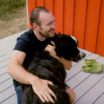 Man hugging his dog outdoors, illustrating kindness, companionship, and the well-being that comes from helping and caring for others.